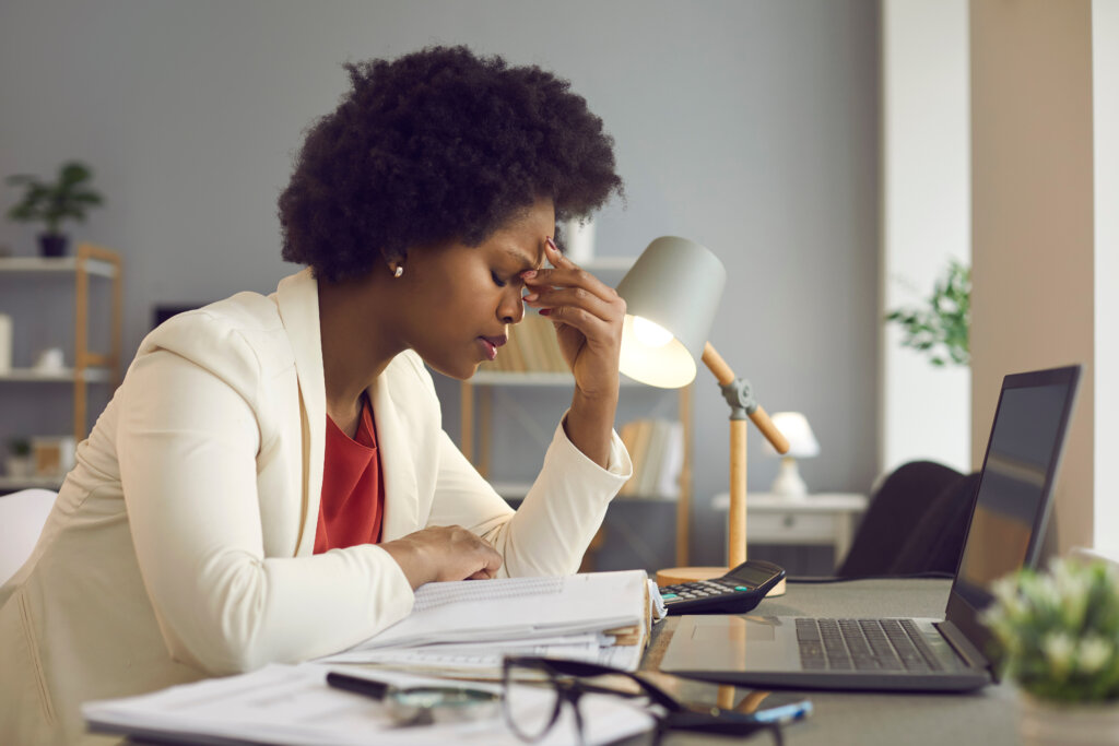 Black executive woman with eyes closed and hand of head, working at laptop for in office